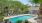 Birds eye view into the fenced pool area, highlighted by the cool blue water  and green palm trees. 